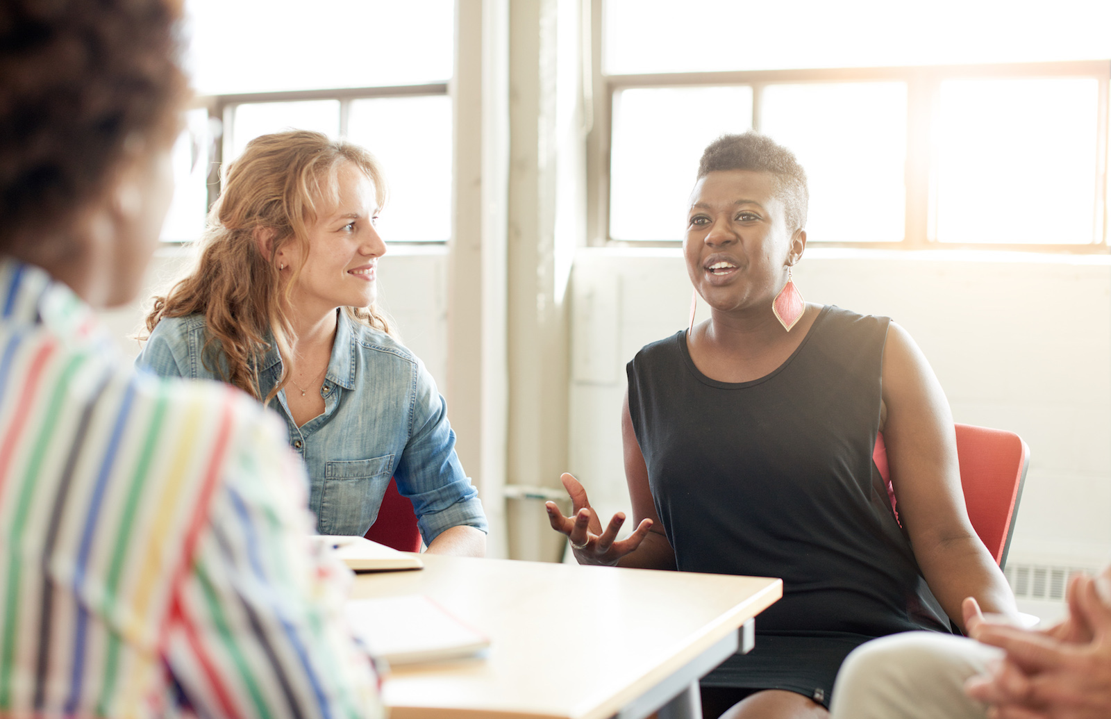 People sitting around a table talking. Focus is on the one person who is talking.